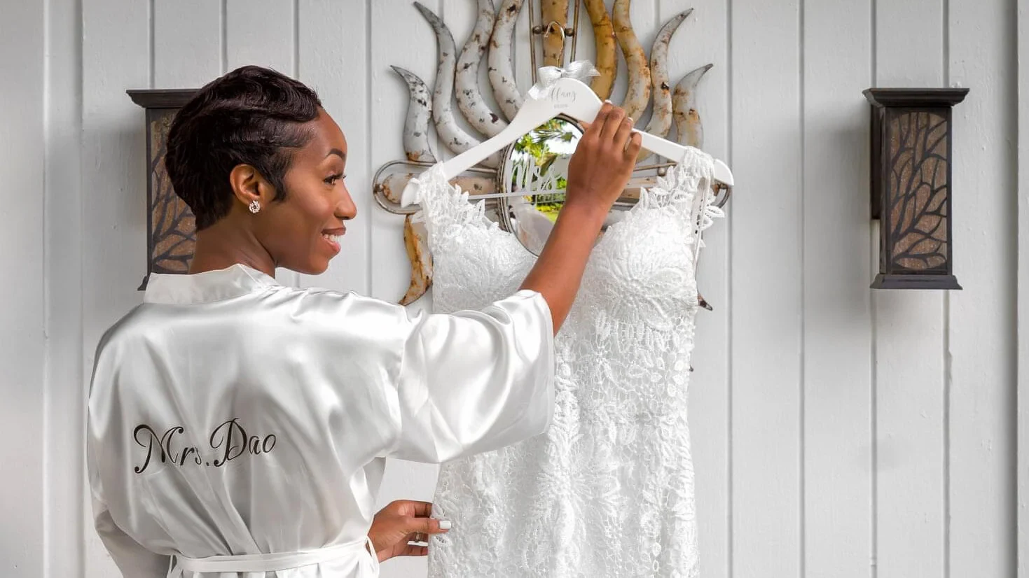 A bride in a satin robe admiring her wedding dress before the ceremony.